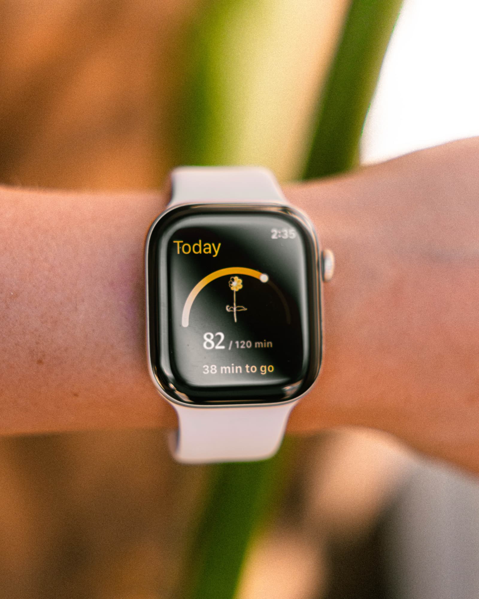 An Apple Watch on a wrist in afternoon light, showing the Rhythm app's Today screen: 82 of 120 minutes of daylight, 38 minutes to go